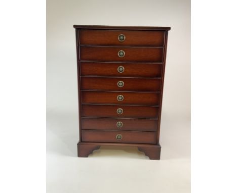 A reproduction music cabinet by John Austin Furniture with regency style handles and bracket feet. Three double drawers below