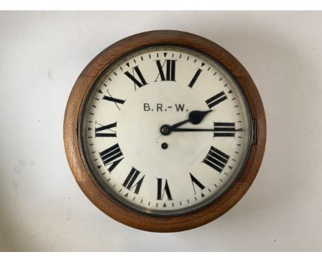 A railway station circular wall clock, the 30cm diameter painted dial with Roman numeral markers and B.R-W., an eight day fus