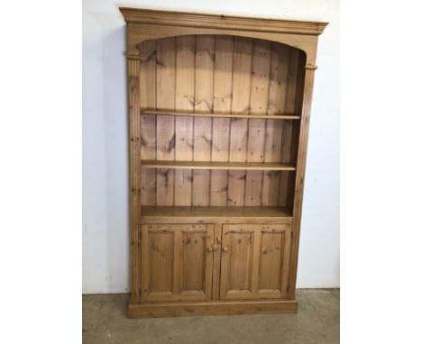 A solid pine book shelf with cupboard below W:126cm x D:27.5cm x H:198cm