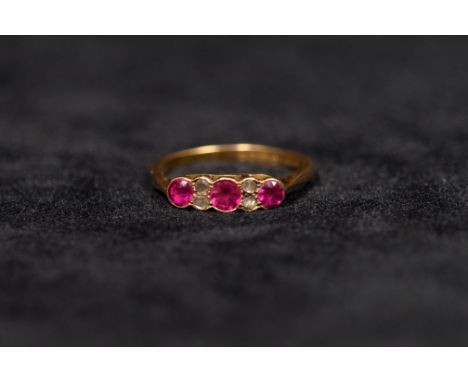 An 18ct gold ruby and diamond ring. Set with three round free cut rubies in colette setting with rose cut diamond accents. 2.