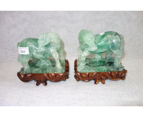 A PAIR OF CHINESE CARVED JADE HORSES, each inset within a hardwood stand, both 17 cm high (including stand)
