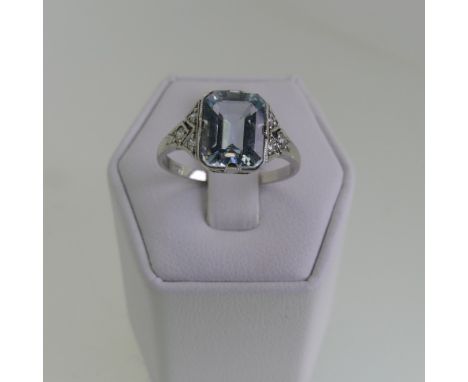 An Art Deco aquamarine and diamond Ring, the central emerald cut aquamarine 8.9mmx7mm, with three millegrain set diamonds on 