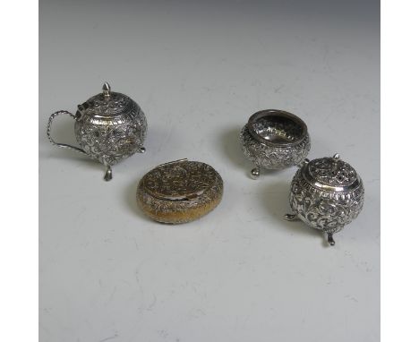 An Indian silver three piece Cruet Set, of circular form with foliate decoration, the mustard with hinged cover, pepper with 