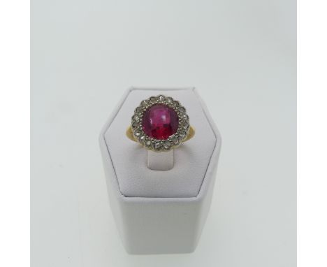 A ruby glass Dress Ring, the circular facetted glass within a surround of rose cut diamonds, all millegrain set, 15mm cluster