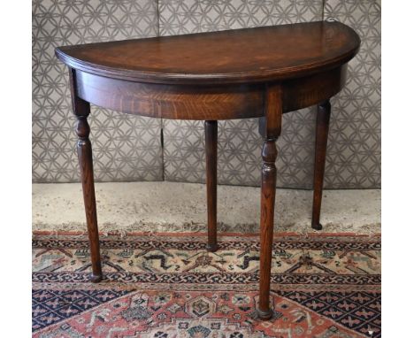 An oak demi-lune fold-over card table with drawer, raised on turned legs, 91 cm x 45 cm (open 90 cm dia.) x 74 cm h 