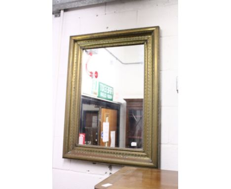 A wall mirror with embossed brass frame.