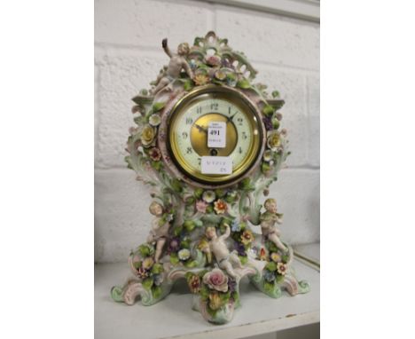 A continental mantle clock, the porcelain body with floral encrusted and cherub decoration.