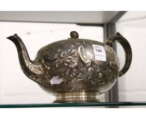 A Victorian silver teapot with embossed decoration.