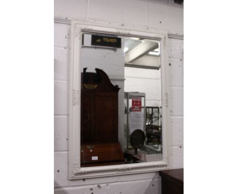 A wall mirror with decorative white painted frame.