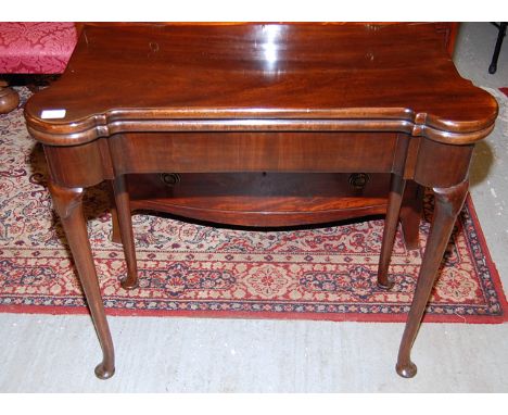 A GEORGE II MAHOGANY FOLDING CARD TABLE, THE TOP WITH CANDLE CORNERS, THE LEGS WITH LAPPETS ON PAD FEET, WIDTH 83 CM 