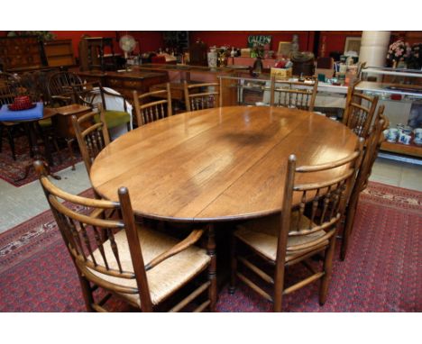 QUALITY SOLID OAK GATE-LEG TABLE AND SET OF EIGHT STICK BACK RUSH SEATED DINING CHAIRS (6 SIDE AND 2 CARVERS) , 230 CM LONG A