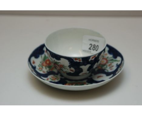 A WORCESTER POLYCHROME TEA BOWL AND SAUCER DECORATED WITH FLOWERS IN RESERVES WITHIN SCALE BLUE 