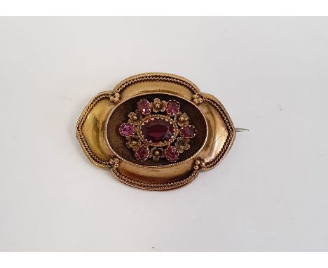 Victorian gold-coloured metal and pink stone brooch, shaped oval, the centre set with faceted ruby/almandine garnets, glass p