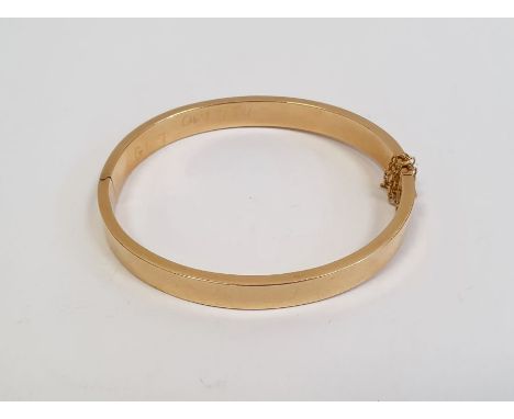 Gold-coloured metal hinged bangle with safety chain, 30g approx.