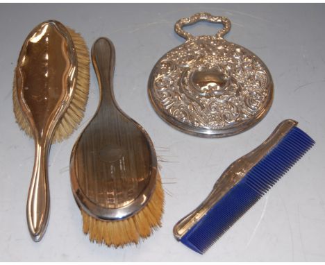 An Edwardian silver hand mirror by Zimmerman &amp; Co together with two silver backed handbrushes and silver mounted comb