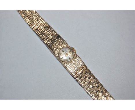 the small round dial with gilt baton quarter hour and black hourly markers, in rectangular textured case and tapered strap, w