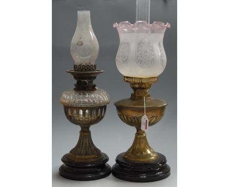 An early 20th century brass pedestal oil lamp, having a pink tinted etched glass shade, h.46cm; together with one other early