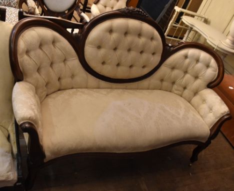 A Victorian walnut framed double end sofa, with carved vine leaves and grapes to the centre back, upholstered in a cream flor