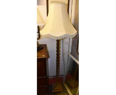 A brass standard lamp with central barleytwist column on four paw feet, height including fitting 130cm.