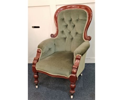 A Victorian green button upholstered fireside armchair on turned feet and castors