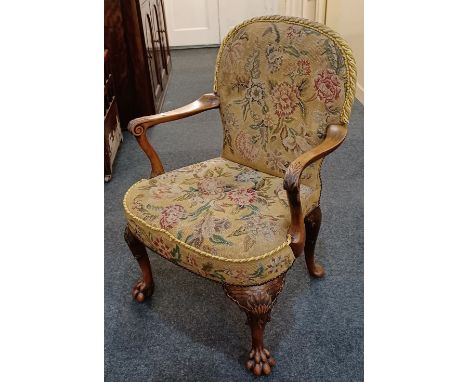 A carved walnut elbow chair with tapestry back and seat, scroll arms on shell carved legs and lion paw feet