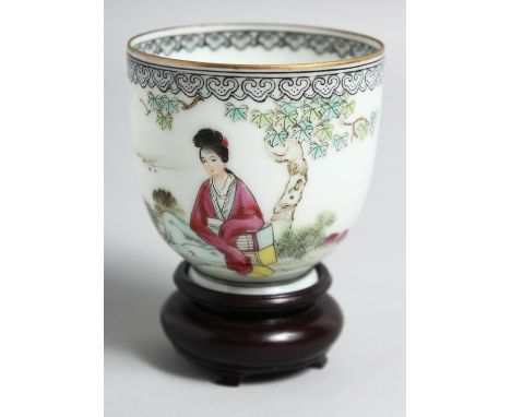 A CHINESE EGGSHELL PORCELAIN CUP AND HARDWOOD STAND, the cup painted with a female figure seated beneath a tree, the reverse 