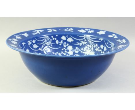 A LARGE CHINESE POWDER BLUE GROUND PORCELAIN BOWL, the interior decorated with various native flora in white. 40.5cm diameter