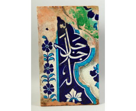 A LARGE ISLAMIC GLAZED POTTERY TILE PANEL with Qur'anic character to the centre. 38cm x 23cm