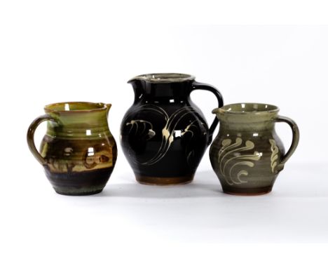 Paul Barron (British 1917-1983), a slipware jug in brown and cream glaze, 16.5cm high, another similar and an olive green and