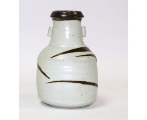 Janet Leach, St Ives Pottery, a stoneware bottle vase, thick cream glaze with tenmoku crossed streaks and rim, twin lug handl