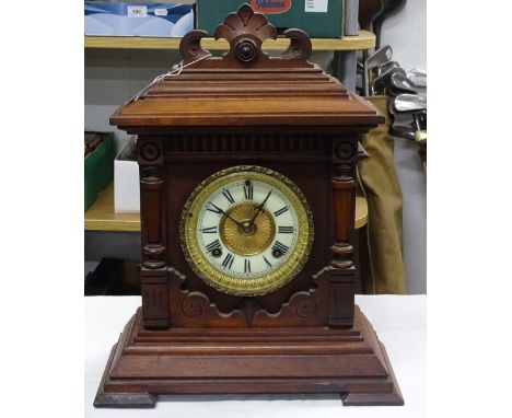 An Antique carved mantel clock with enamel and brass dial.