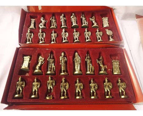 Two Christos Arapatsakos cast metal chess sets, King H: 10 cm (one gold pawn damaged), boxes are poor. P&amp;P Group 2 (£18+V