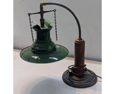 An Industrial style desk lamp having a vintage 1940s green enamel railway lamp shade on a later brass and turned wooden stand