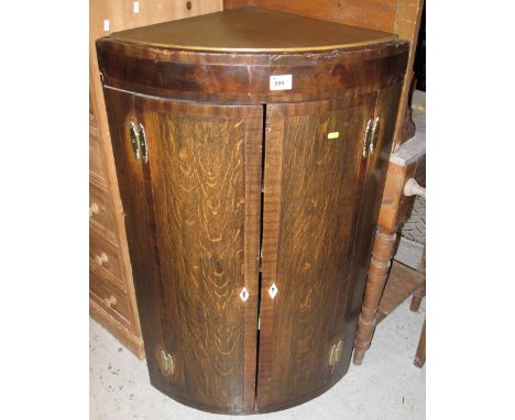 Early 19th Century bow front, blind panelled corner cabinet on associate modern stand.