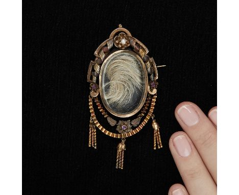 Victorian gold tone metal locket brooch with two hinged swags from which three bell shaped flowers hang, each suspending thre