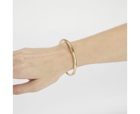 Italian 14k yellow gold hinged bangle of oval shape. Marked 14kt Italy with unidentified marker's mark on the interior clasp.