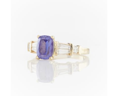 14 yellow gold ring set with central oval tanzanite accompanied by two tapered baguette cut diamonds and one brilliant cut di