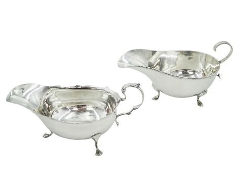 Two early 20th century silver sauce boats, the first example with flying scroll handle, upon three hoot feet, hallmarked Walk