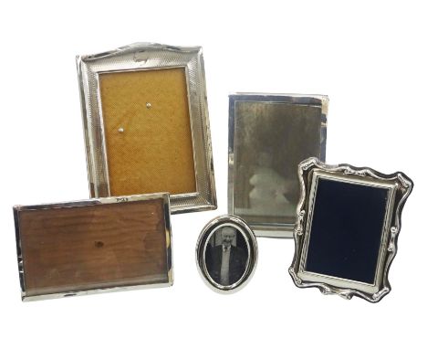 Five silver mounted photograph frames, the largest example with curved top, vacant circular panel and engine turned decoratio