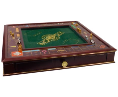 A wooden Monopoly board, together with playing tokens, game accessories, and Real Estate Portfolio, the board 52cm wide. 