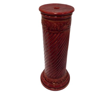 A Burmantofts red glazed pottery jardiniere stand, decorated in relief with two bands of flowers and leaves above a spiral tw