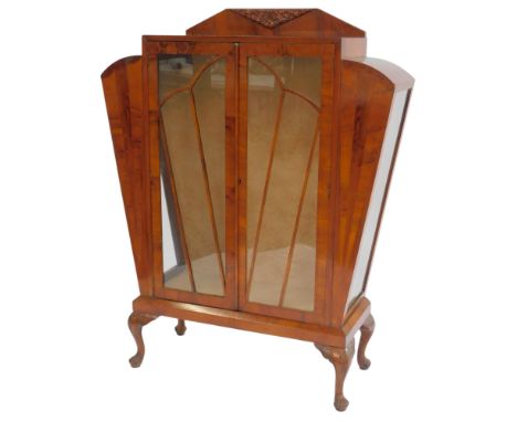 An Art Deco mahogany and walnut display cabinet, the top with a raised back carved with flowers, the base with two glazed doo
