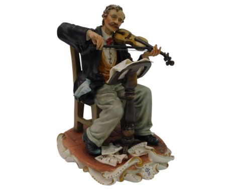 A Capodimonte porcelain figure, modelled as a seated gentleman playing the violin, 22cm high. 