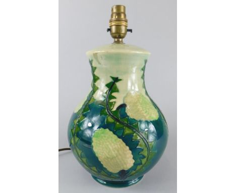 A Moorcroft pottery lamp base, decorated with a design of thistles, on a blue ground, impressed mark to underside, 92cm high 