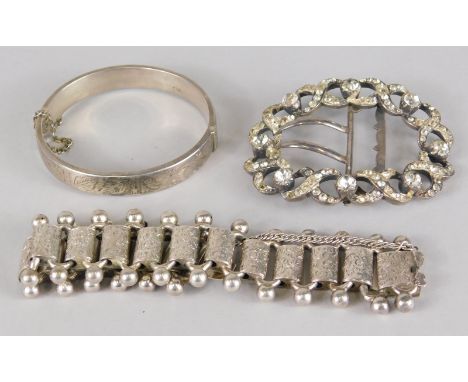 Three items of jewellery, to include a paste stone set buckle, a silver bangle, and a floral silver bracelet. 