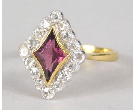 An 18ct gold ruby and diamond dress ring, with central diamond cut ruby, surrounded by tiny diamonds, in rub over settings, 4