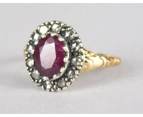 A ruby and diamond dress ring, with central oval cut ruby, surrounded by twelve diamonds, set in a dark background, with flor