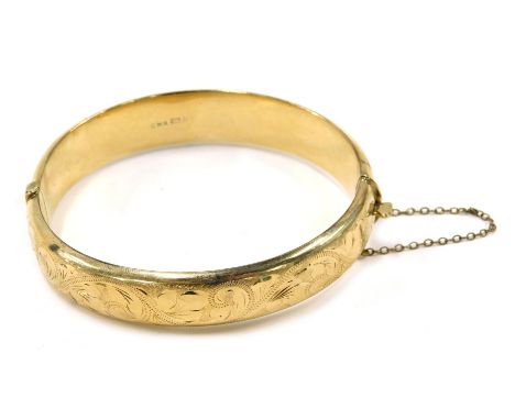 A 9ct gold hinged bangle, with half scroll design, with safety chain, maker CMR, Birmingham, 6cm diameter. 