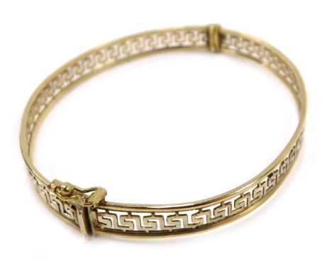 A hinged bangle, with Greek key pierced centre design, on white gold finish with a yellow metal border stamped Italy 375, 6.5