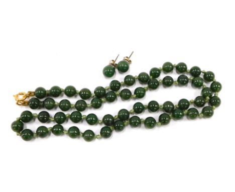 An imitation jade necklace and earring set, with oval beads, on a knotted green string stand with gold plated circular bolt r
